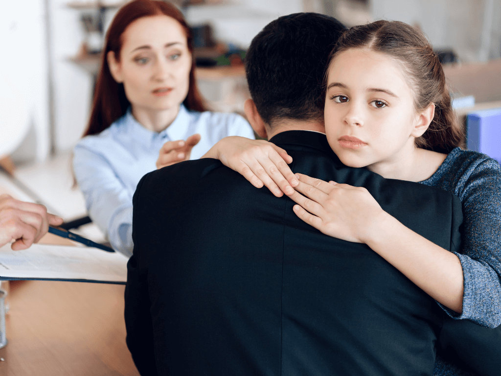 daughter sadly hugging her father in front of her mother