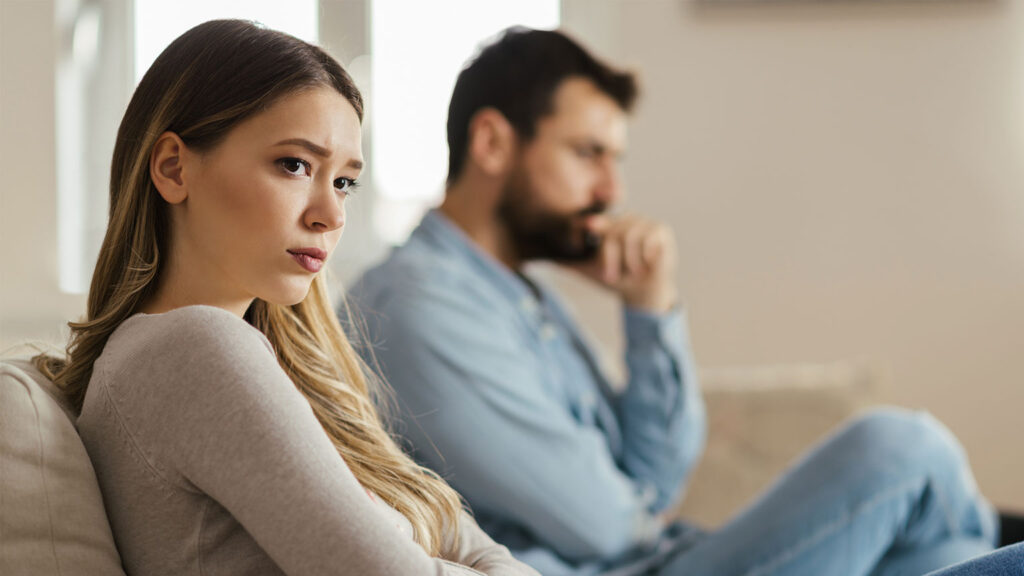 couple sitting apart on couch upset