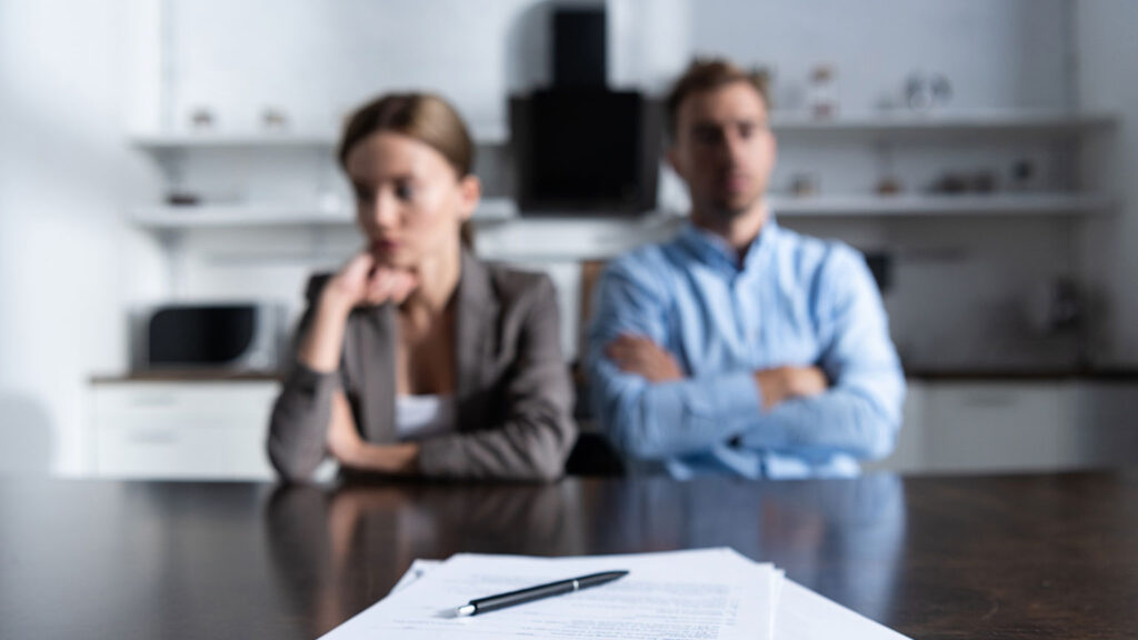 upset couple sitting at table with documents in front of them