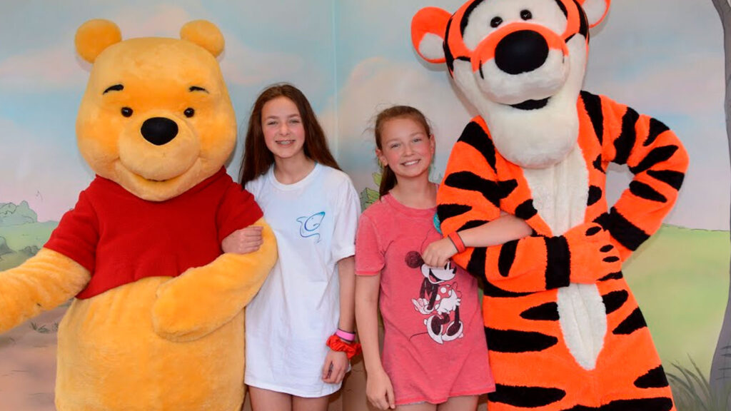 girls holding arms with Winnie the Pooh and Tigger