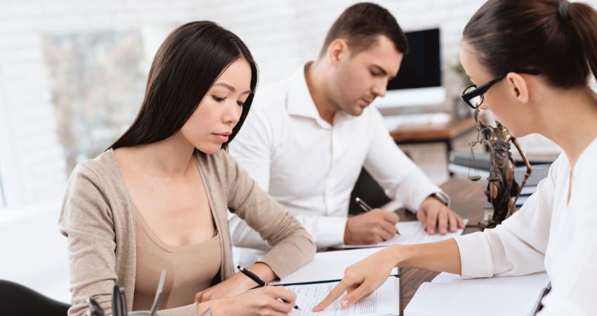 Couple signing paperwork in front of a lawyer