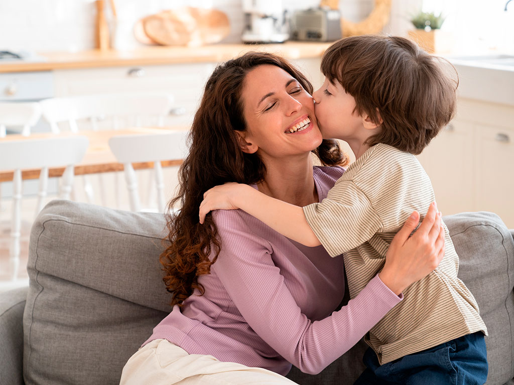Mother hugging adopted son in Texas while sitting on a couch 