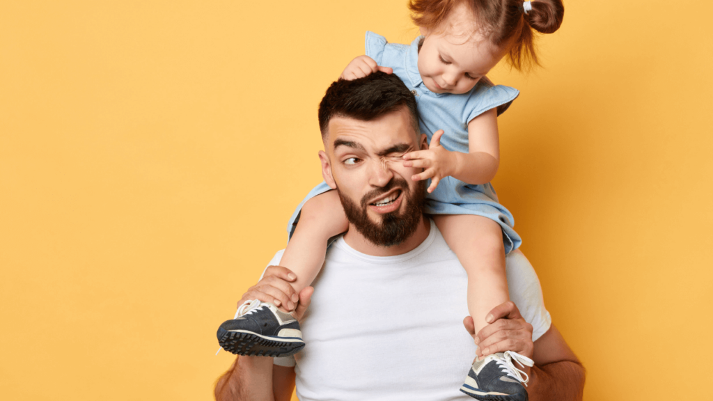 A dad holding his daughter on his shoulders