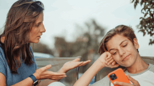 Mother trying to talk to her teenage child who looks distracted on a smartphone.