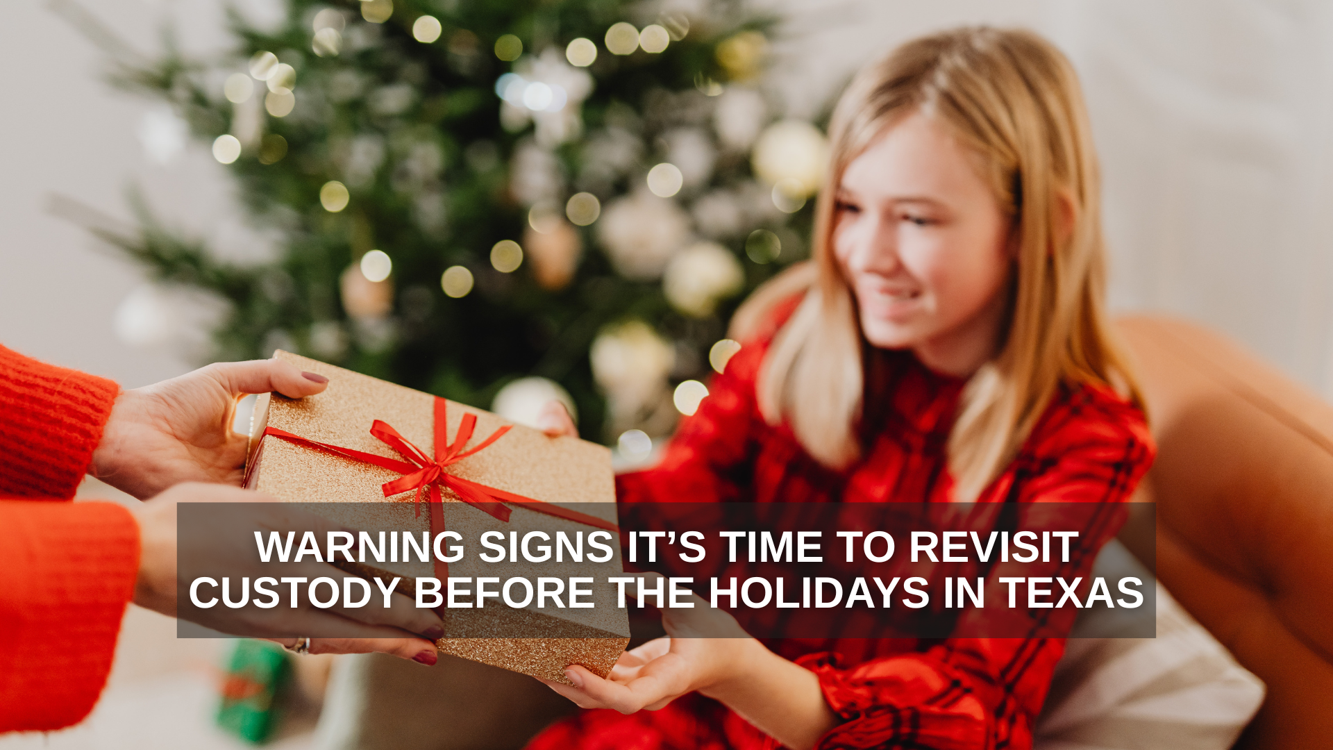 A smiling teenage girl in a red plaid outfit receives a wrapped Christmas gift from an adult in front of a decorated holiday tree, representing family connection and holiday custody moments in Texas.