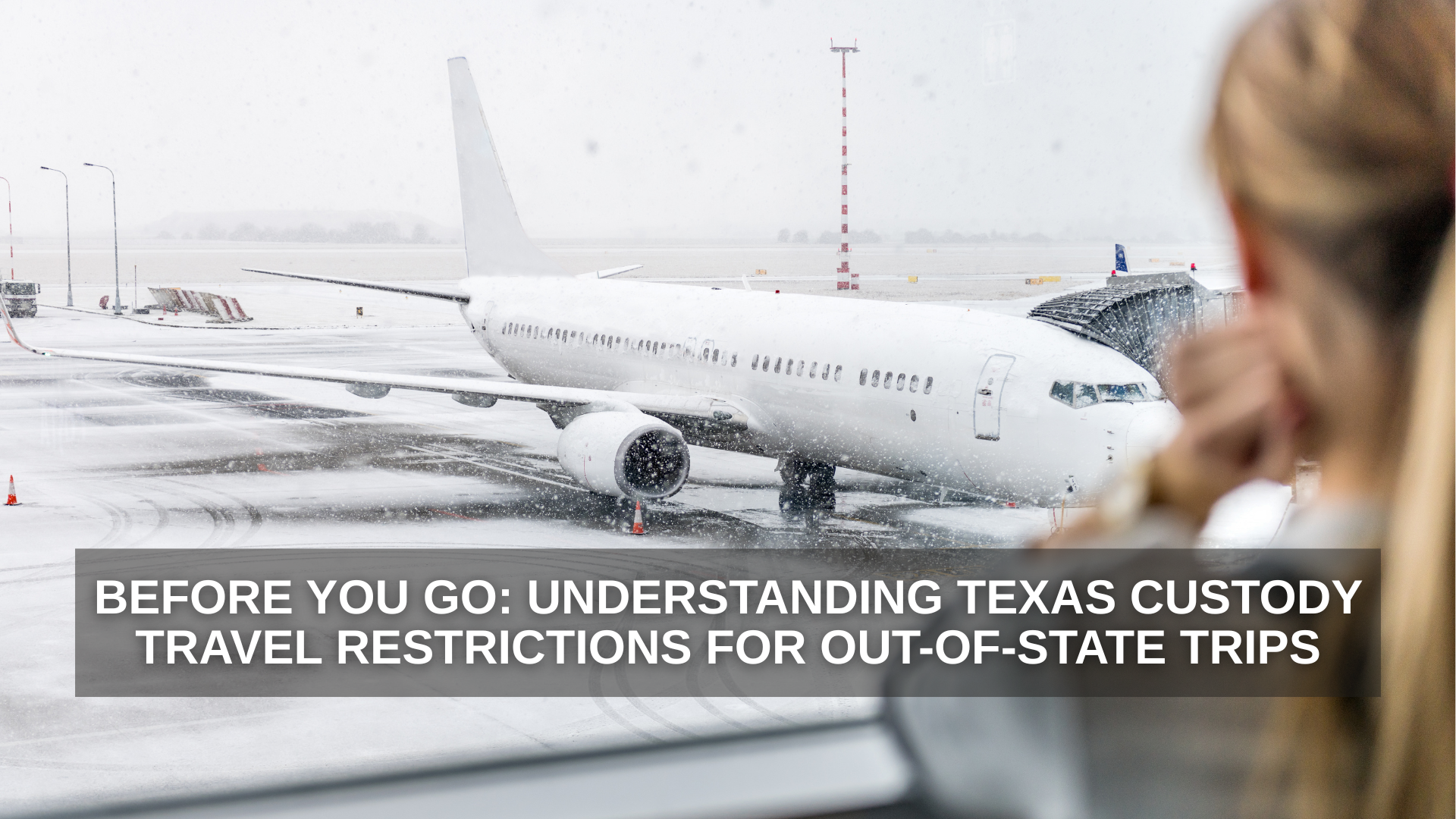 A woman looks out an airport window at a snow-covered runway where a passenger airplane is preparing for departure
